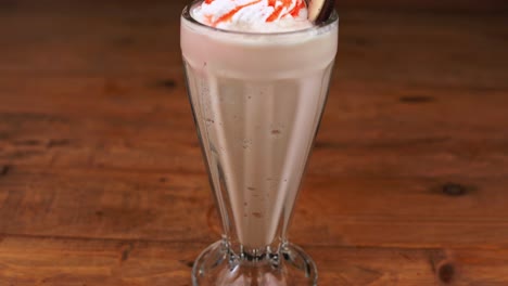 Detailed-close-up-of-chocolate-milkshake,-with-caramel,-espresso-and-whipped-cream-and-caramel,-tilt-down