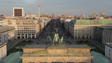 Antena:-Acercándose-Lentamente-A-La-Puerta-De-Brandenburgo-Y-Al-Tiergarten-Bajo-La-Hermosa-Luz-Del-Sol-Del-Atardecer-Con-Una-Vista-Cercana-De-La-Estatua-Verde-Quadriga-En-Berlín,-Alemania