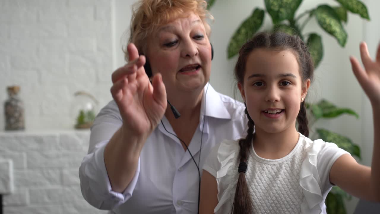 작은 소녀와 할머니가 헤드폰을 들고 집에 있습니다.