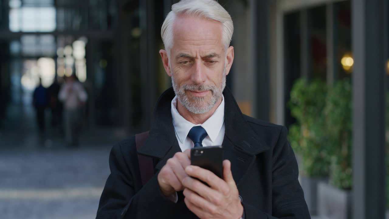 portrait successful mature businessman using smartphone in city enjoying texting browsing messages on mobile phone happy senior entrepreneur communicating online slow motion