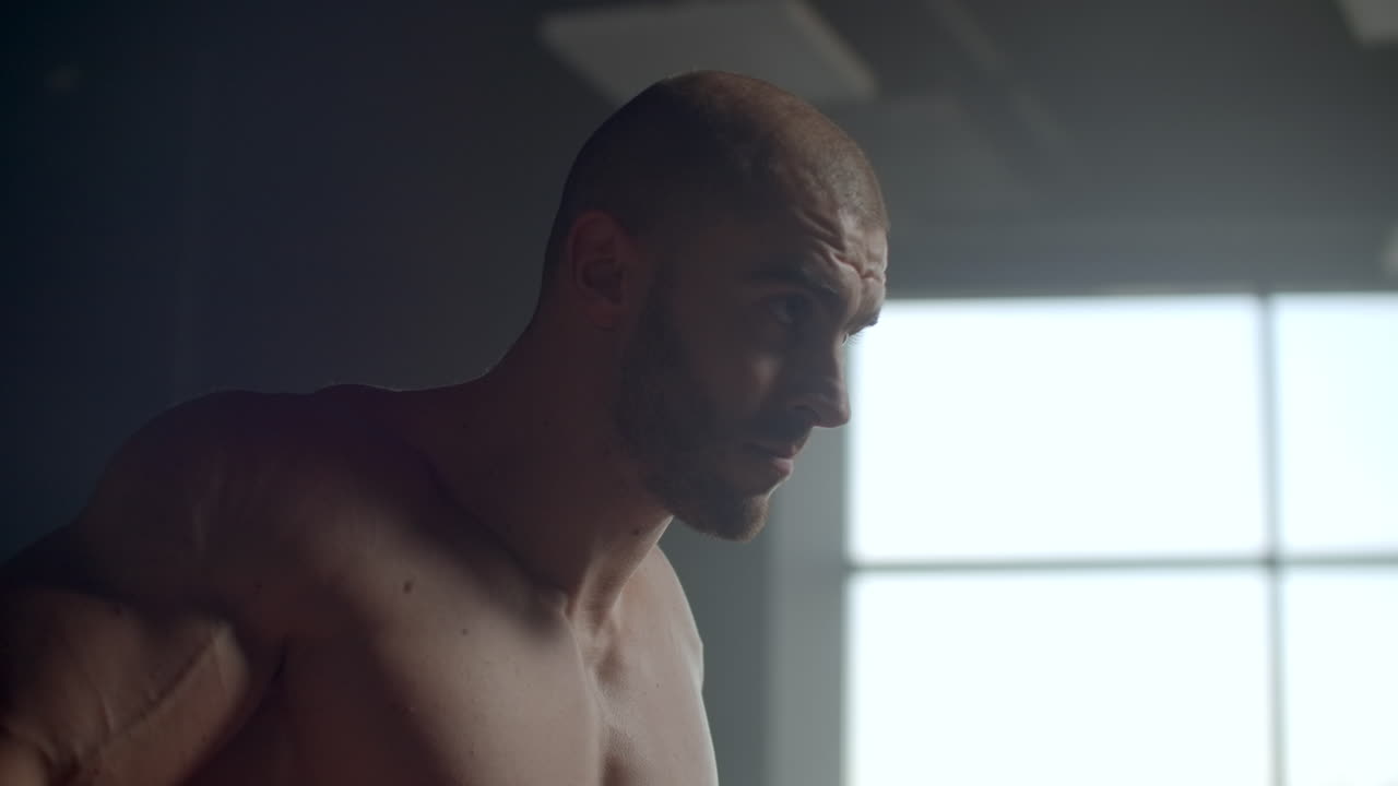 hombre atlético fuerte levanta pesas entrenamiento de los músculos trapezoides.