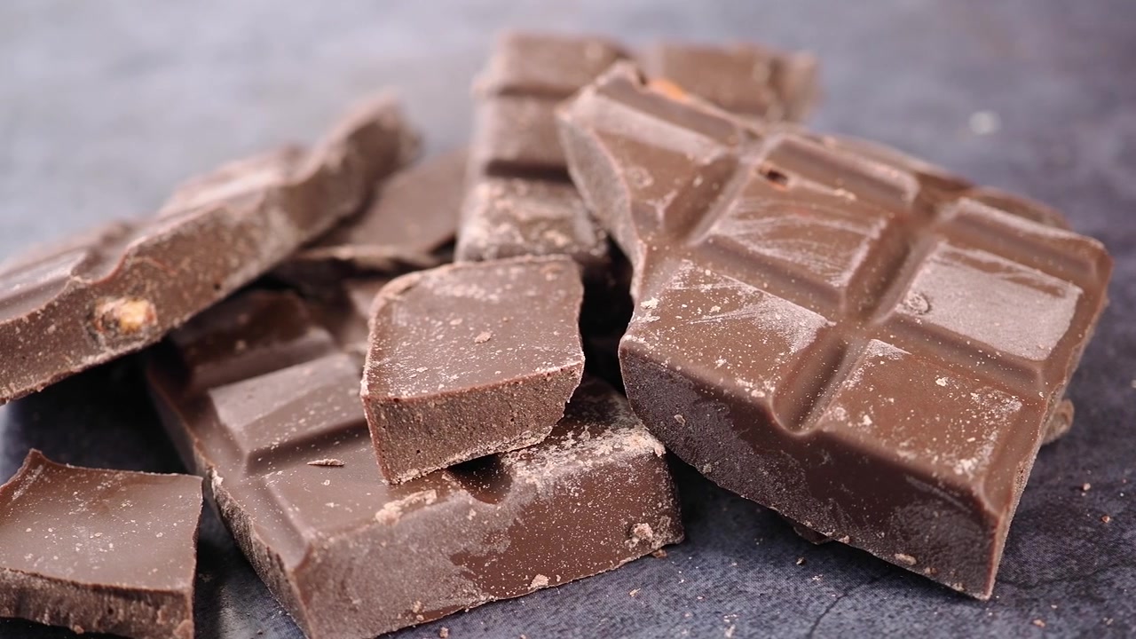 Pezzi di cioccolato fondente spezzati su una superficie scura