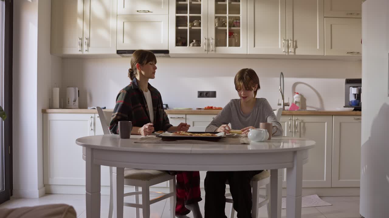Mother and son sharing pizza in the kitchen