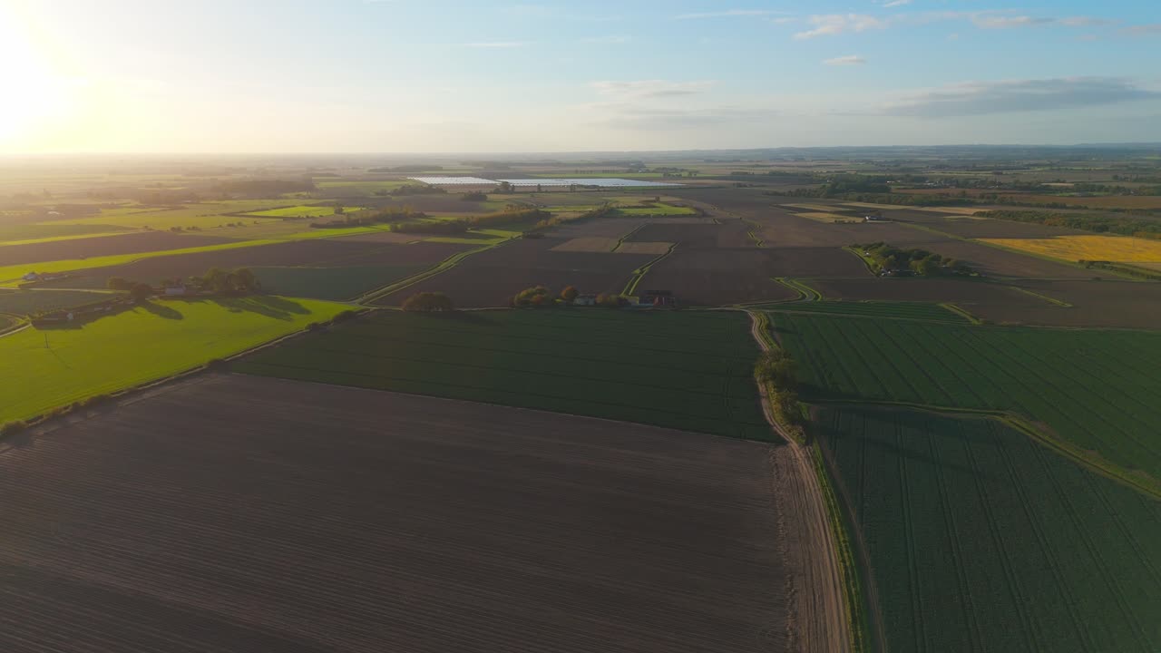 Rural Agricultural footage of Lincolnshire farmland with crops growing in patchwork fields on the east coast of Britain. Acres of farmland surrounded by small rural village home