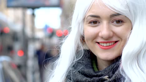 una joven sonriente y graciosa con una perla blanca en la calle.