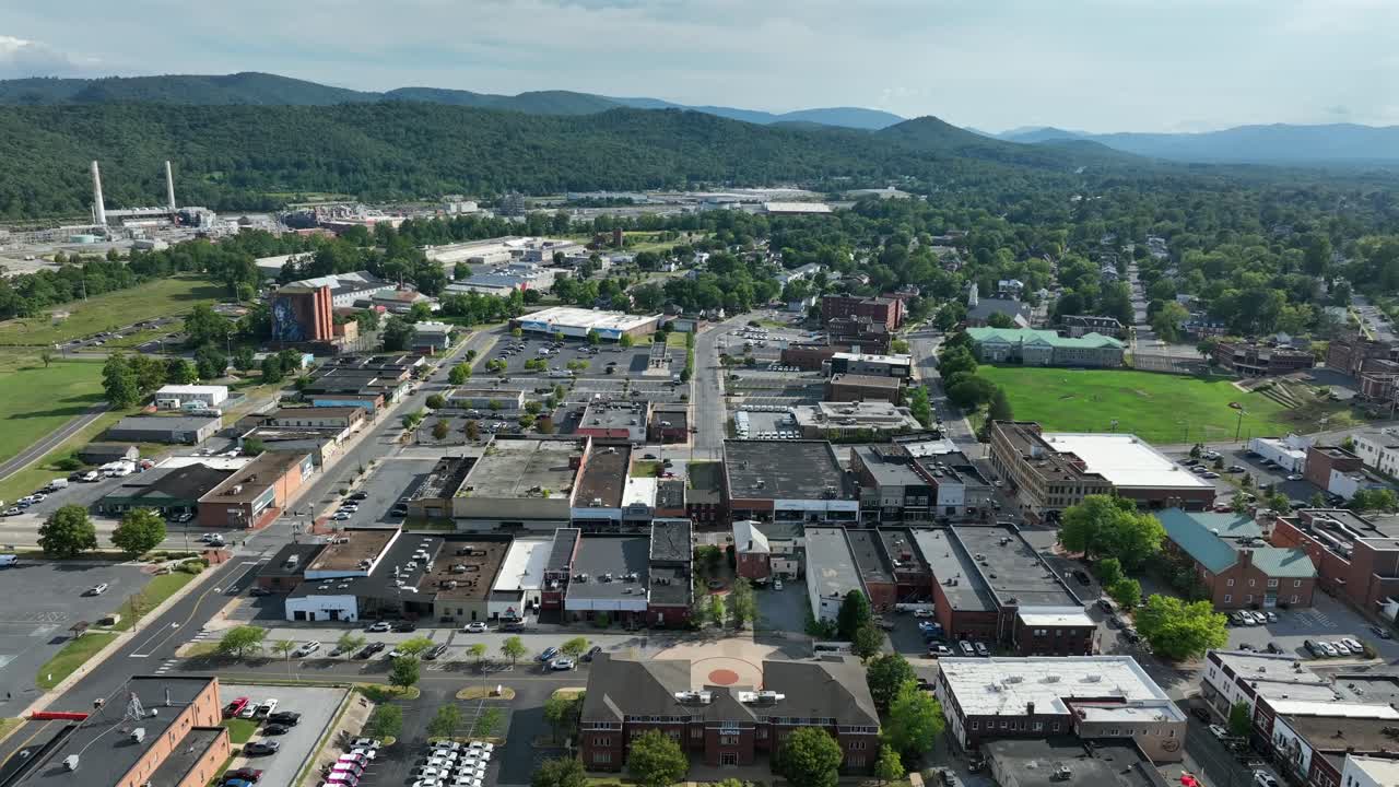 Traditional American town with roofs or townhouses and idyllisch mountain range in background. Aerial wide shot. Sunny summer day with green forest trees, charming old city in Virginia