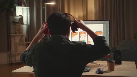 asian male mobile application developer start works with graphics on his personal computer. he works late at night