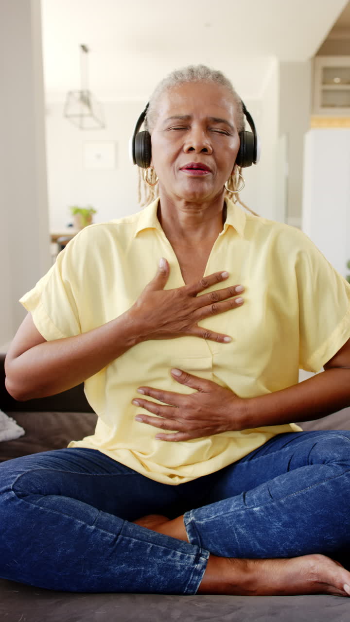 Vertical video: Elderly African American woman closes eyes, enjoys music, hand on chest