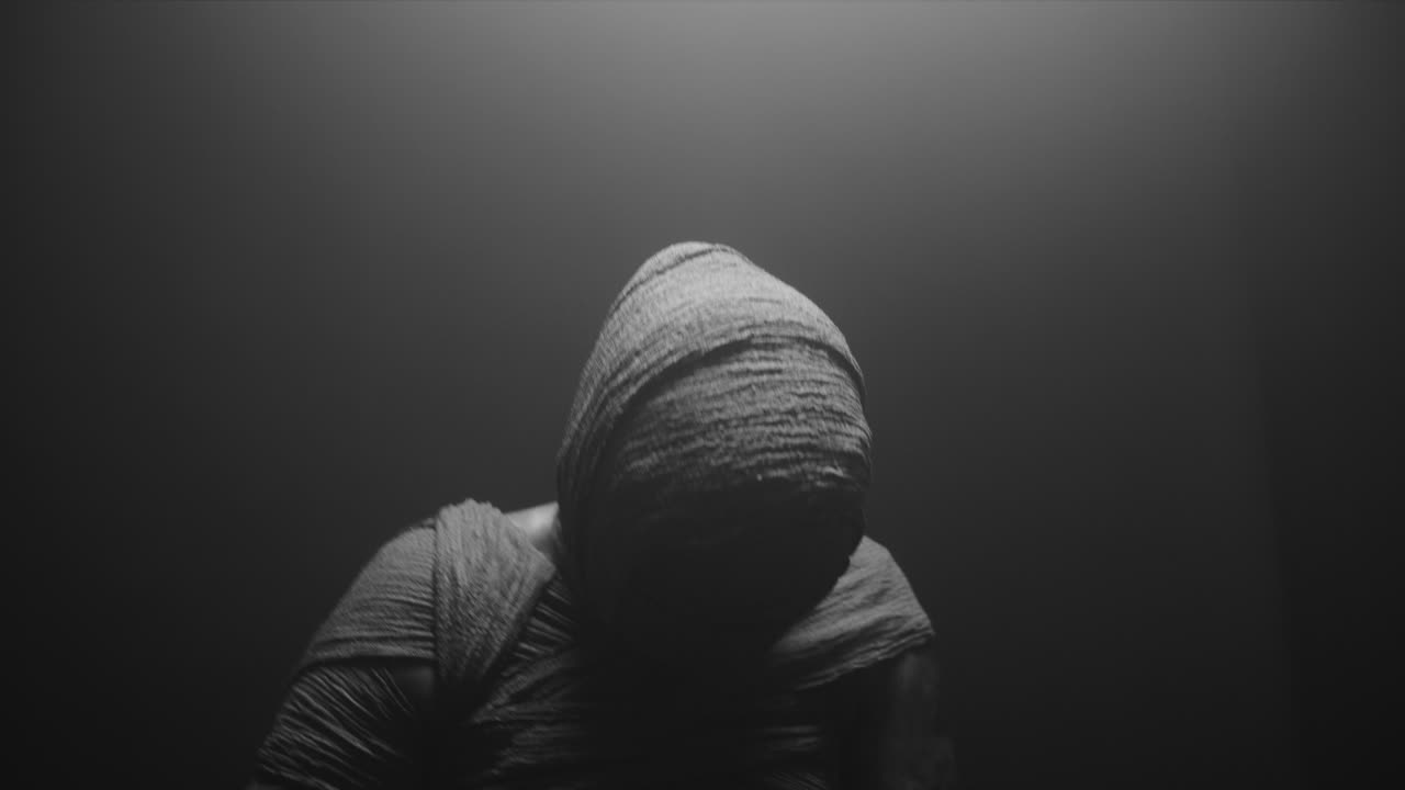 A mummy of a woman on a dark backdrop slowly rises her head