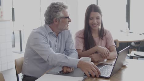 empresarios felices hablando y usando laptop