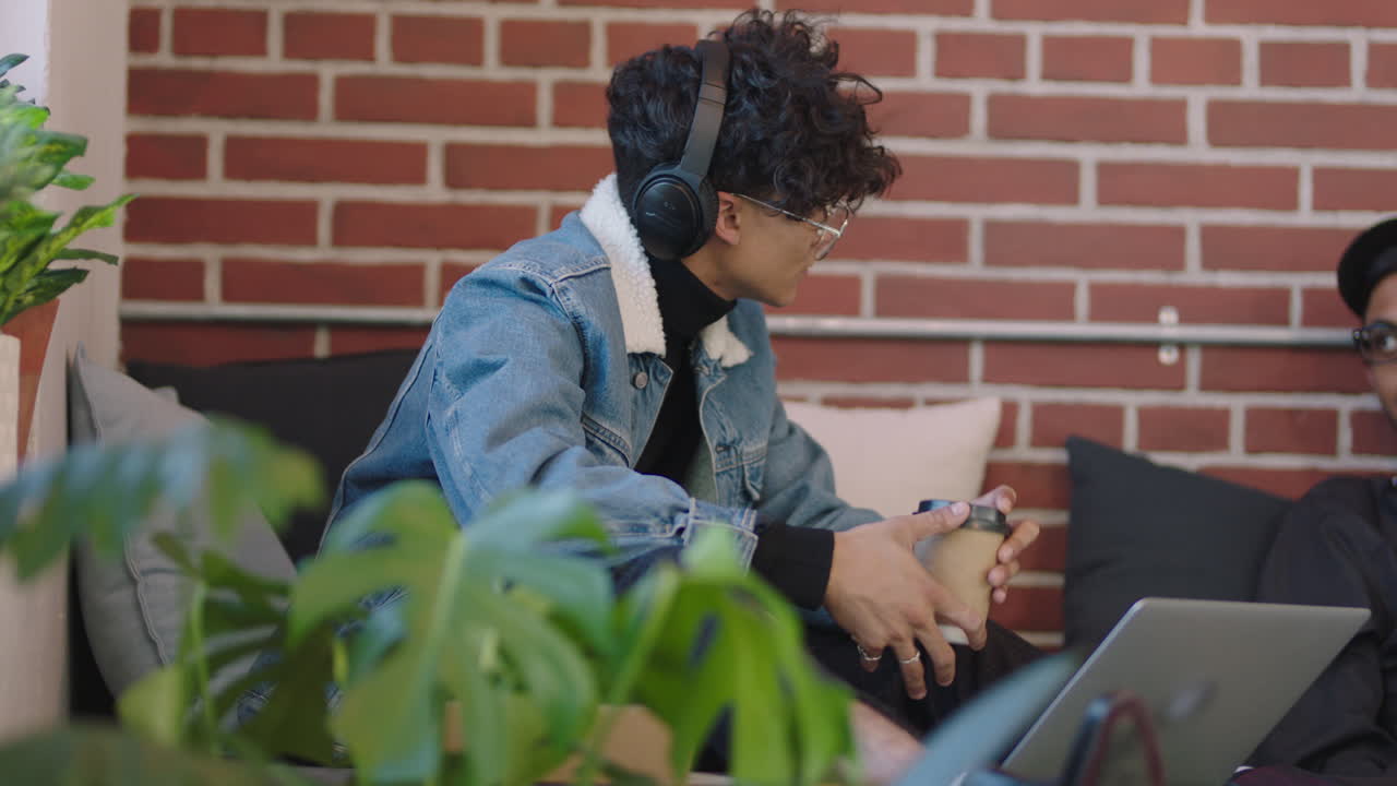 joven estudiante de negocios hispano usando computadora portátil estudiando en línea disfrutando de trabajar escuchando música relajándose en un moderno lugar de trabajo de oficina usando auriculares