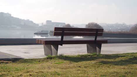 empty wooden bench by a river on a foggy morning