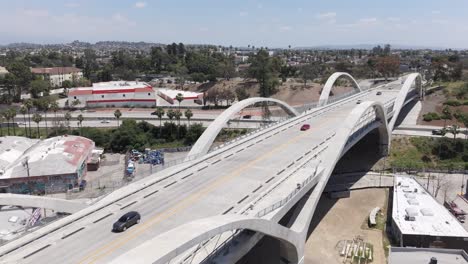 vehículos conduciendo en el puente de la calle 6 en los ángeles como el tráfico cruzado se mueve a lo largo de la autopista en el fondo, tirón aéreo