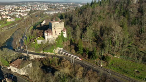 Beautifull-historical-Schloss-Angenstein-builded-on-a-hill-while-a-modern-passanger-train-is-driving-through-the-tunnel-in-the-Swiss-landscape