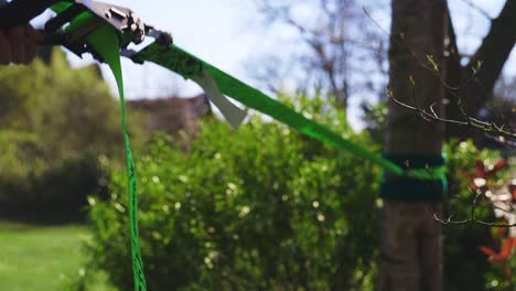 over the shoulder of man disassembling bright green slack line