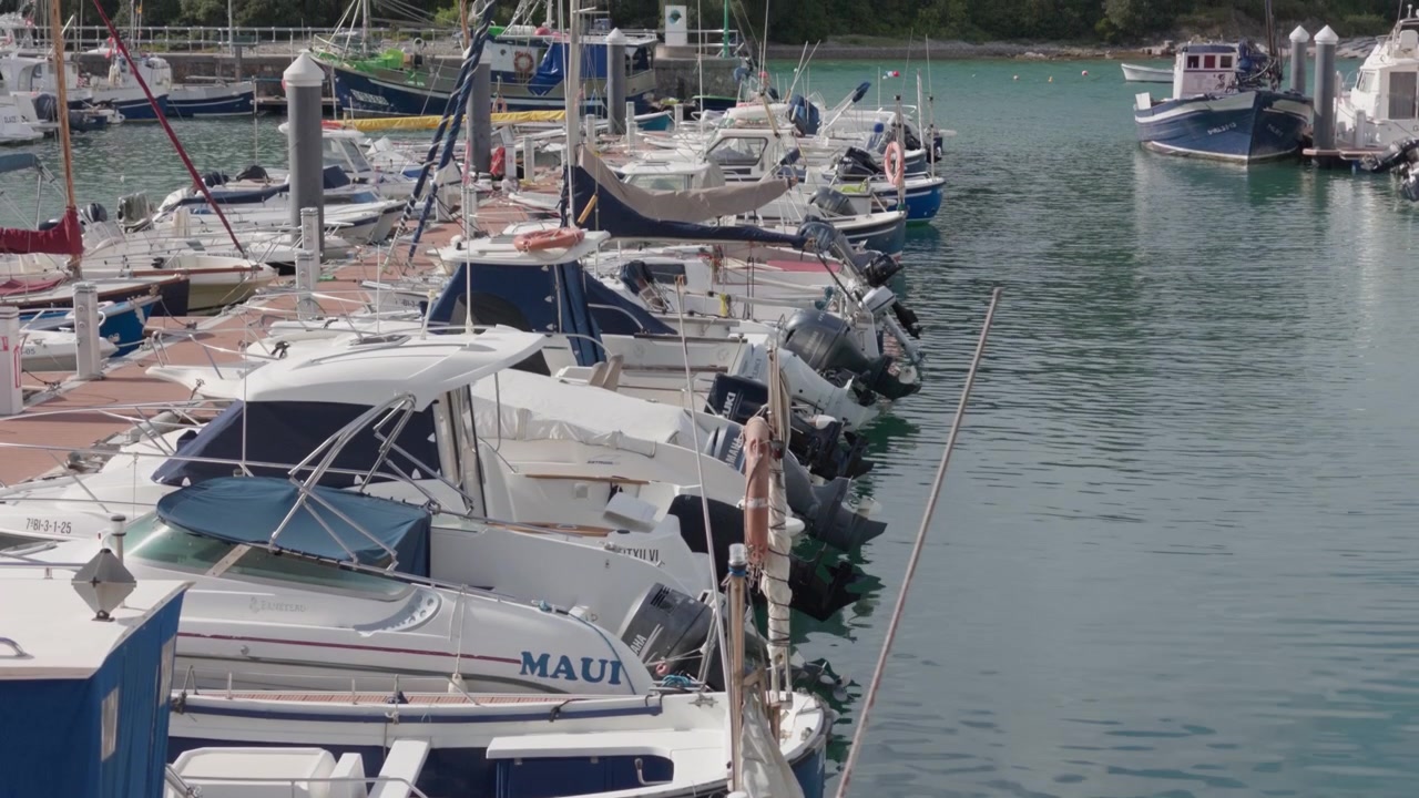 Barche da diporto ormeggiate lungo un molo in un porto soleggiato, che riflettono uno stile di vita costiero rilassato e i viaggi di piacere nei Paesi Baschi