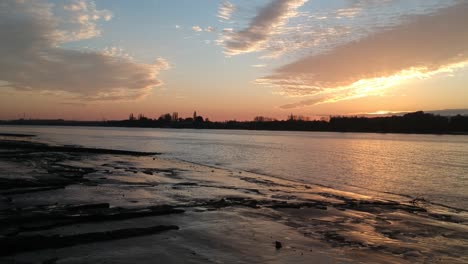 Flying-towards-silhouette-of-city-on-coastline-of-Schelde-river