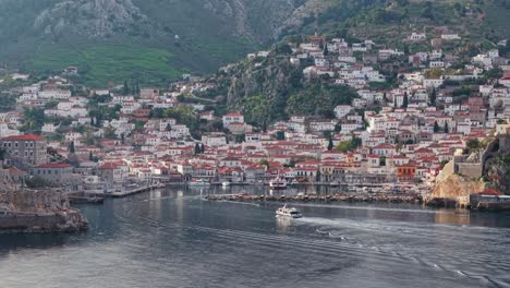 aerial drone footage of a taxi boat entering the picturesque harbor of hydra, greece. island life, maritime motion, and traditional charm from above