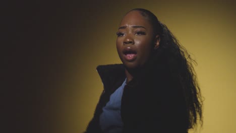 head and shoulders studio portrait shot of young woman dancing in spotlight against yellow background 6