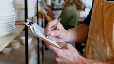 Male-pottery-maintaining-record-on-clipboard-4k