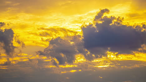 golden clouds drift across a vibrant yellow-orange sky during a beautiful sunset timelapse