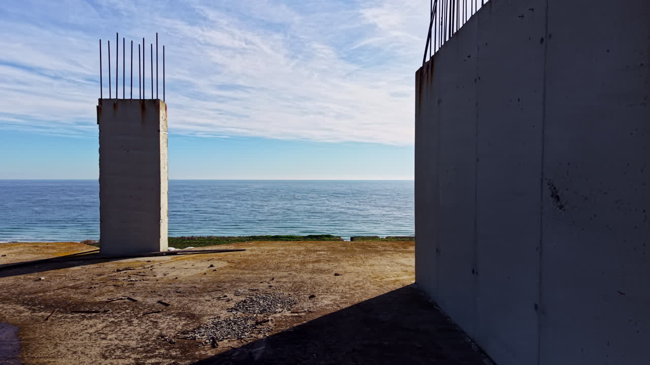 Cantiere edile con vista sull'oceano in un paesaggio costiero che mette in risalto i pilastri sotto il cielo blu e l'acqua tranquilla all'alba o al crepuscolo