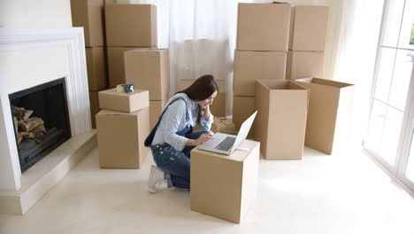 mujer joven usando una computadora portátil en una caja de cartón