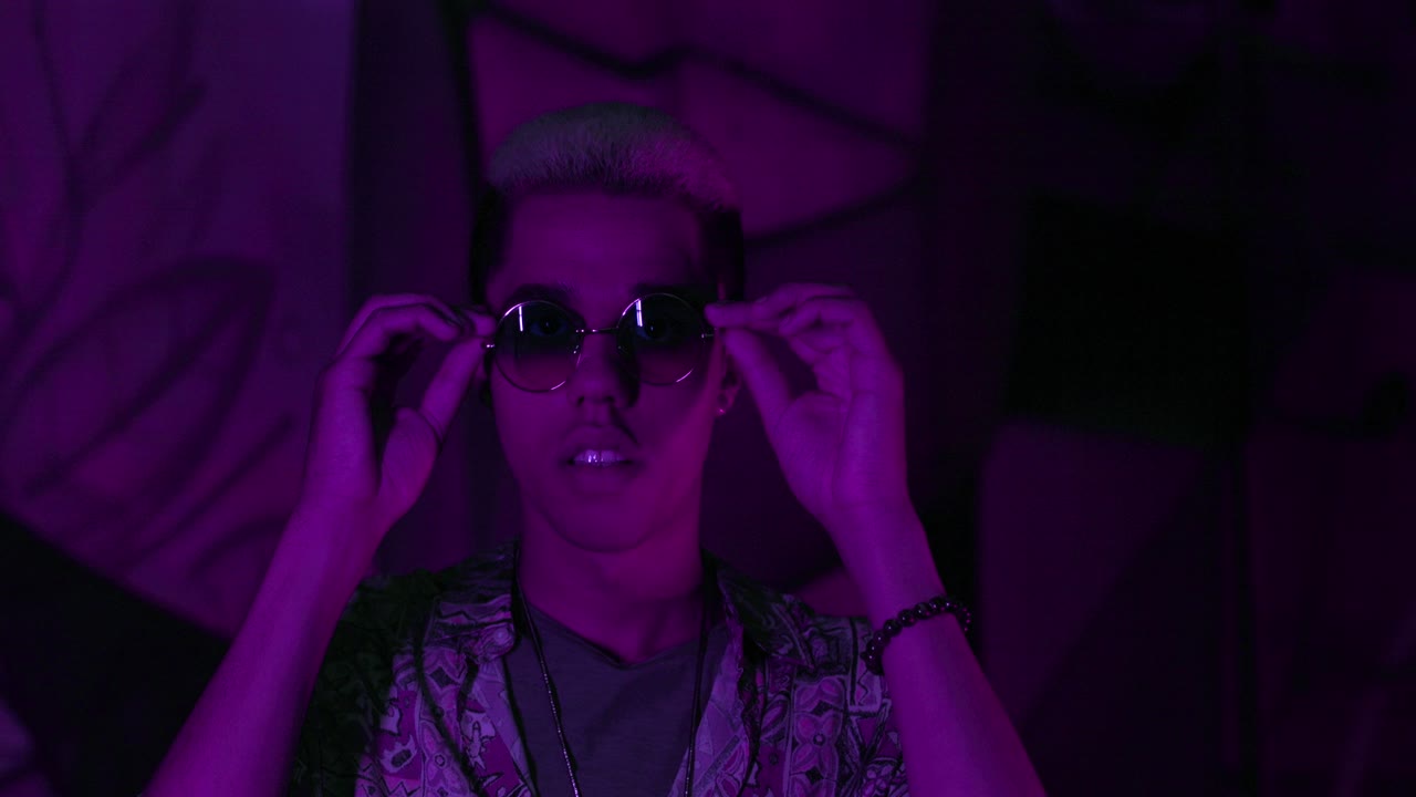 vista de cerca de un joven afroamericano con estilo poniéndose las gafas y divirtiéndose en una fiesta por la noche