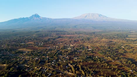 Amanecer:-Paisaje-De-Kenia-Con-Un-Pueblo,-Kilimanjaro-Y-El-Parque-Nacional-De-Amboseli---Seguimiento,-Vista-Aérea-De-Drones