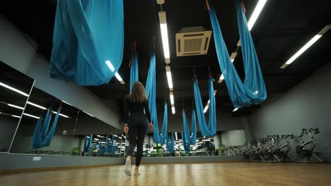 attractive woman doing aero yoga stretching exercises in hammocks at fitness studio. healthy lifestyle for female. workout gym