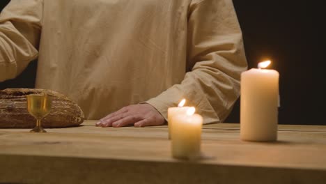 close up shot of man wearing robes with long hair and beard representing figure of jesus christ with bread and wine preaching