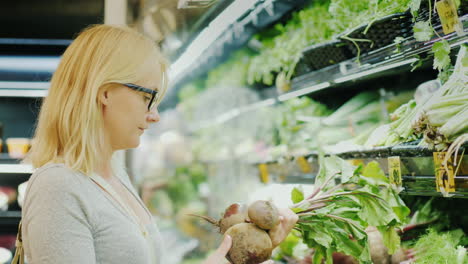 young woman picks beets in the vegetable department of the store