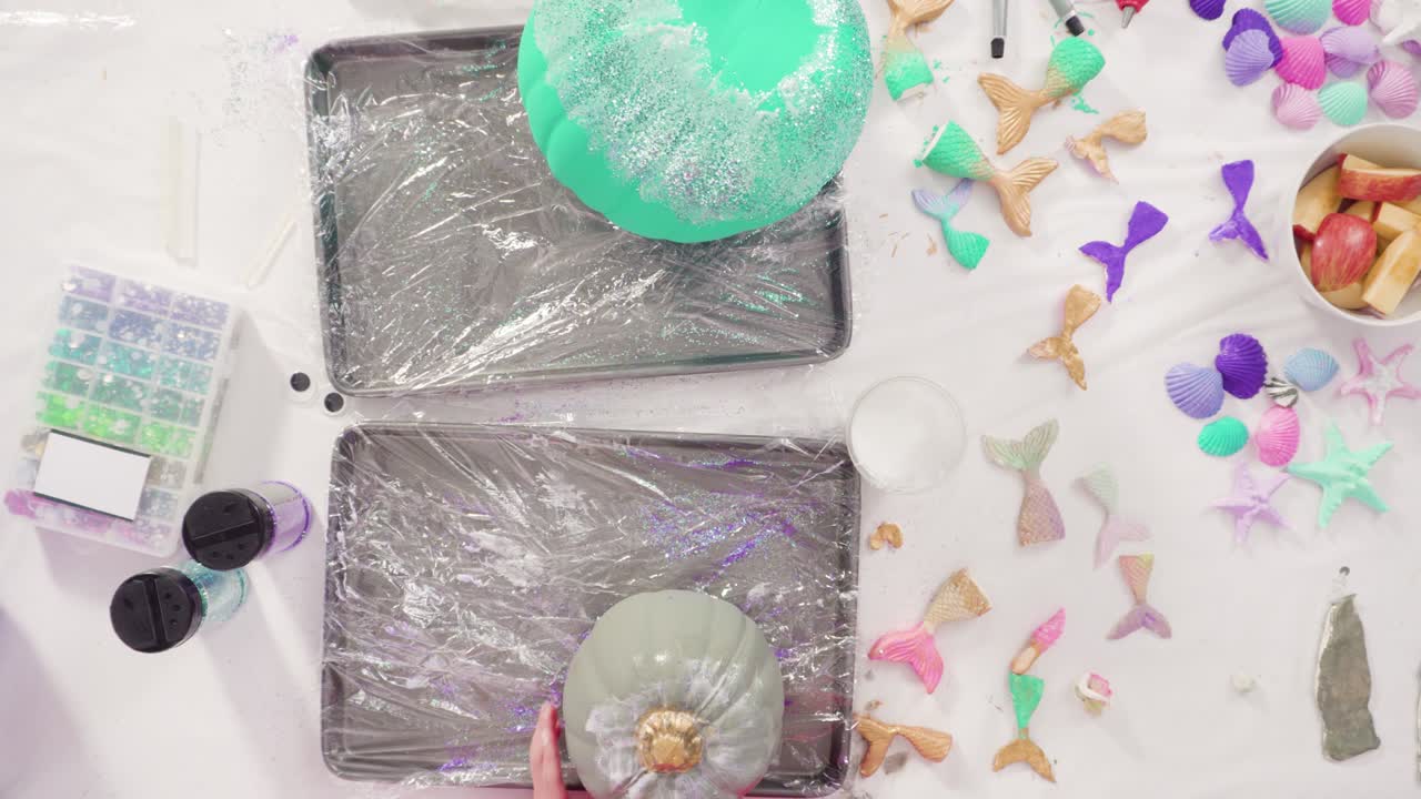 Decorating art pumpkins with glitter in mermaid theme for Halloween.