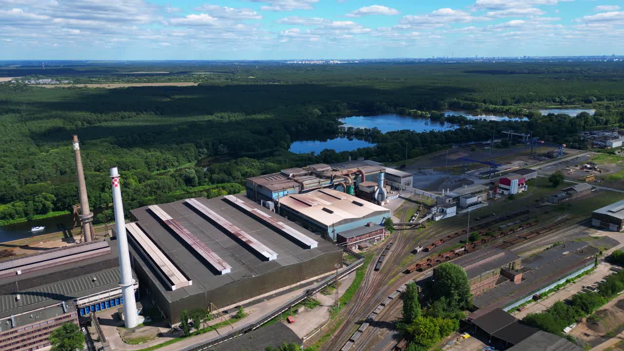 Hennigsdorf Steel Mill showcasing its industrial operations, chimneys, vast railway network, and surrounding landscape. Nice aerial view flight drone shot from above