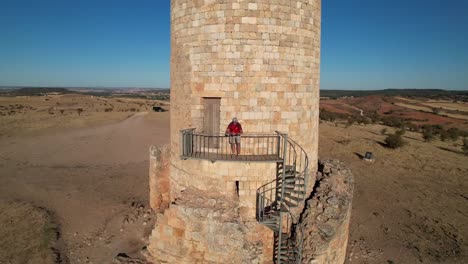 Hombre-De-Mediana-Edad-Vestido-Con-Una-Camisa-Roja,-Pantalones-Cortos-De-Camuflaje-Y-Una-Gorra-En-Una-Torre-De-Vigilancia-Islámica-En-Soria,-España