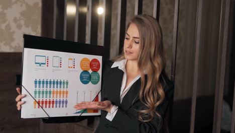 nice adult girl in a business suit shows a presentation on infographics looking at the camera