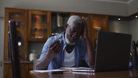 stressed african american senior man using laptop and calculating finances at home