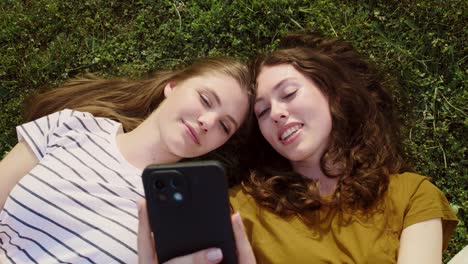 top view of best friends lying on grass with mobile phones