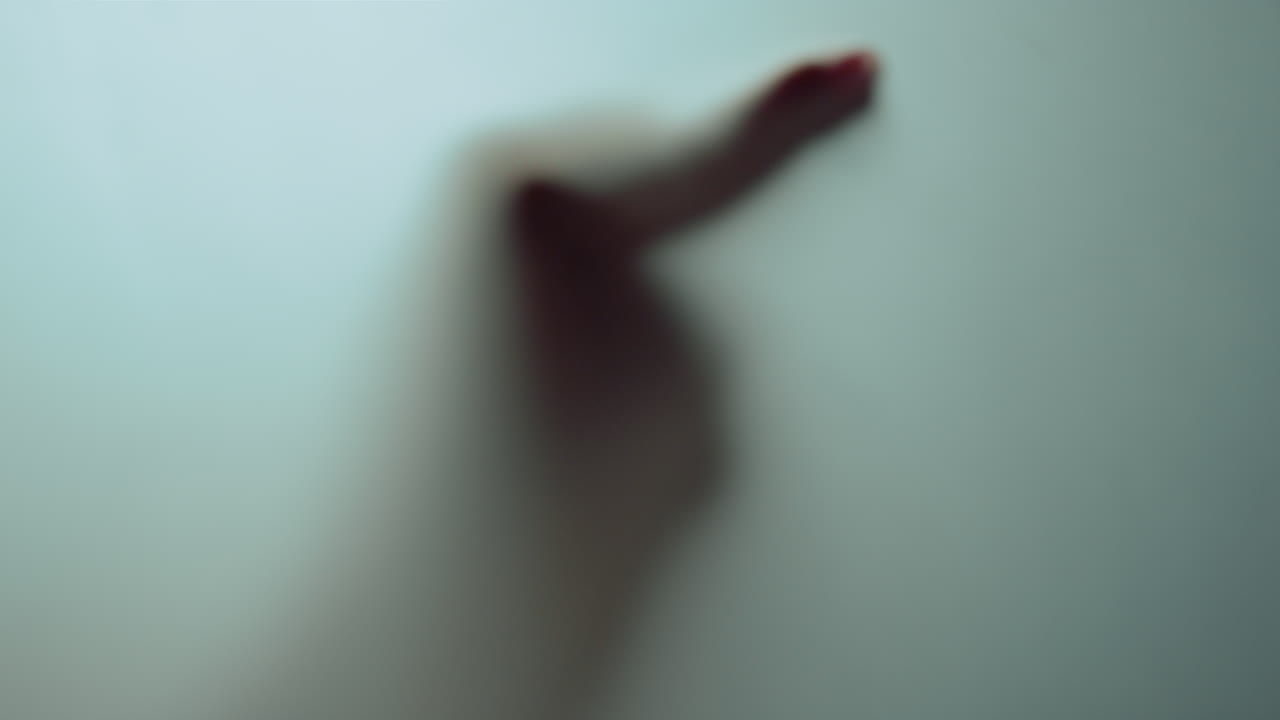 추상적인 초점이 맞지 않는 손이 마스팅된 유리 뒤에 나타납니다. 흐릿한 움직임.