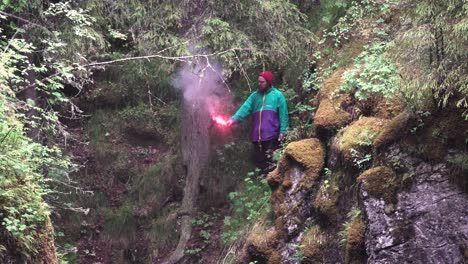 hombre con llamarada de humo rosa en el bosque