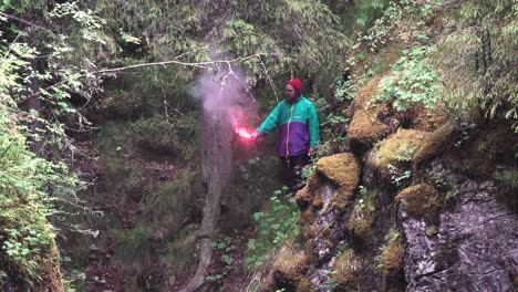 man with pink smoke flare in the woods