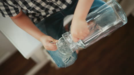 child pouring water into a glass