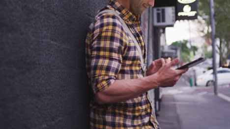 Caucasian-male-lying-on-a-wall,-using-a-tablet-with-his-bike-next-to-him