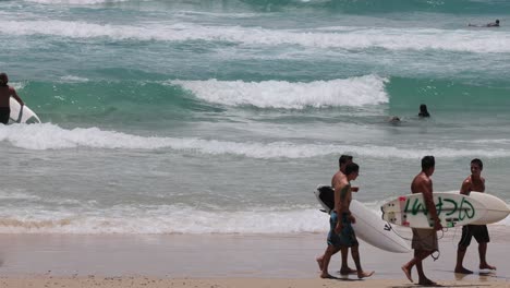 group of surfers walking by the sea, waves crashing