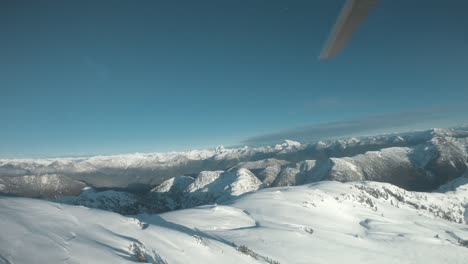 imágenes de gran angular de un helicóptero aterrizando en una montaña nevada en canadá bc, con cielos despejados cerca de la puesta del sol