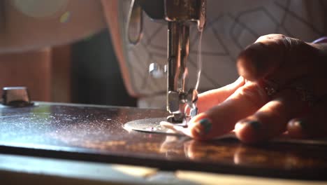 a seamstress running single stitches along the folded edges of a cloth mask in agra, uttar, pradesh in india - closeup shot