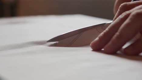 close up of cutting through fabric on a table with scissors slowly.