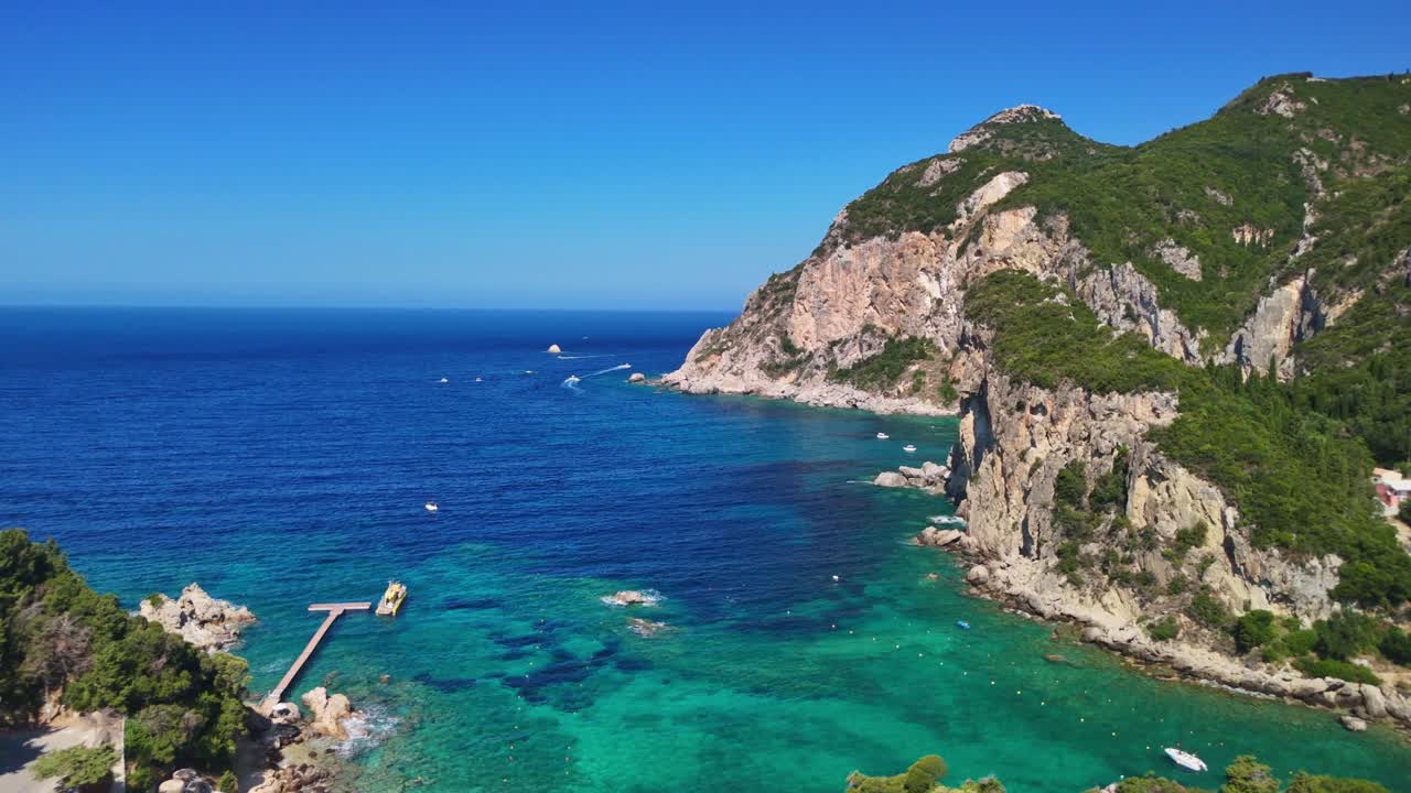 Sunny aerial view of turquoise sea bay with rocky cliffs and boats