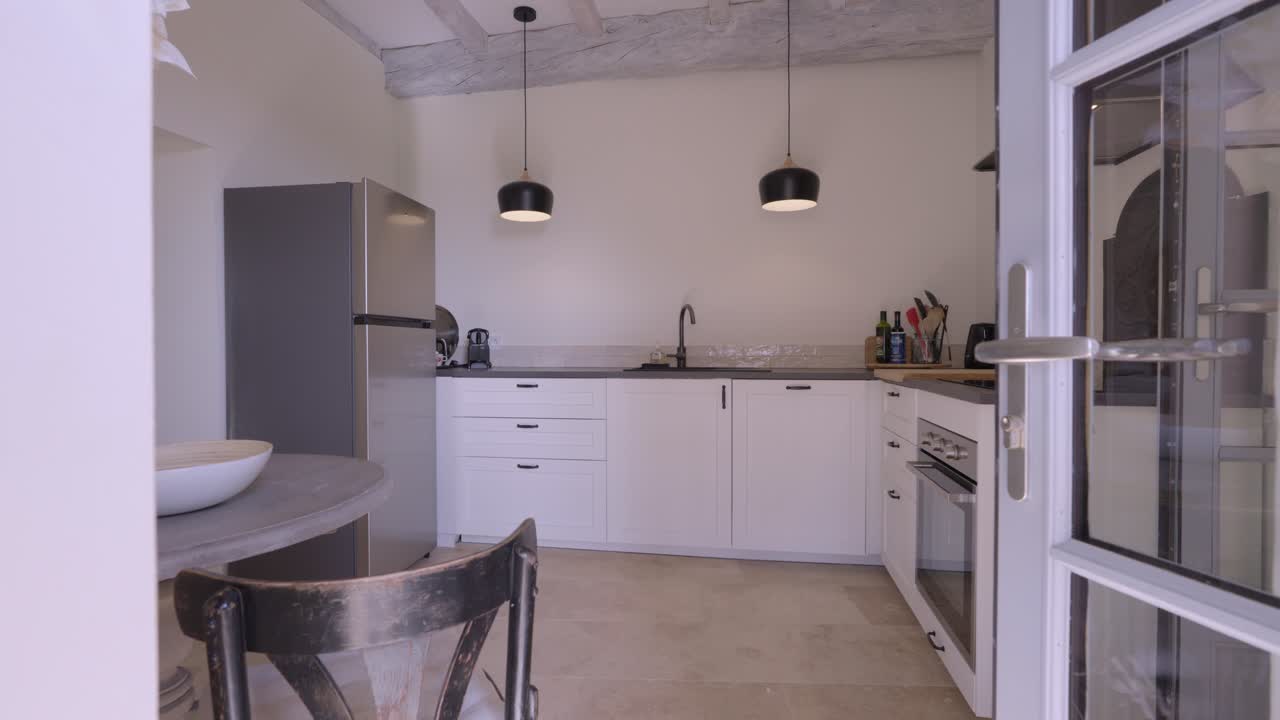 Slow motion establishing shot of a beautiful grey and white kitchen with table