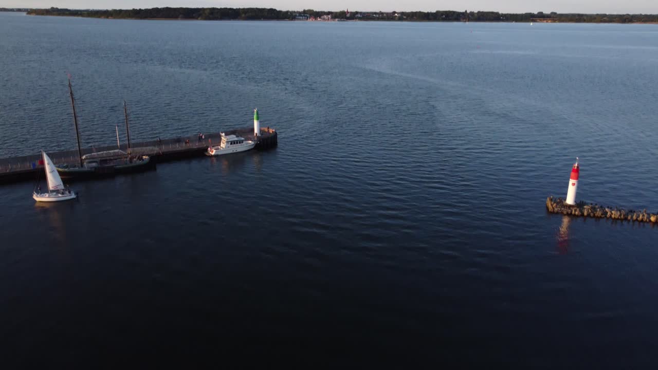 entrada al puerto deportivo, una pequeña lancha motora está conduciendo en el puerto de atraque, las reversas revelan la vista